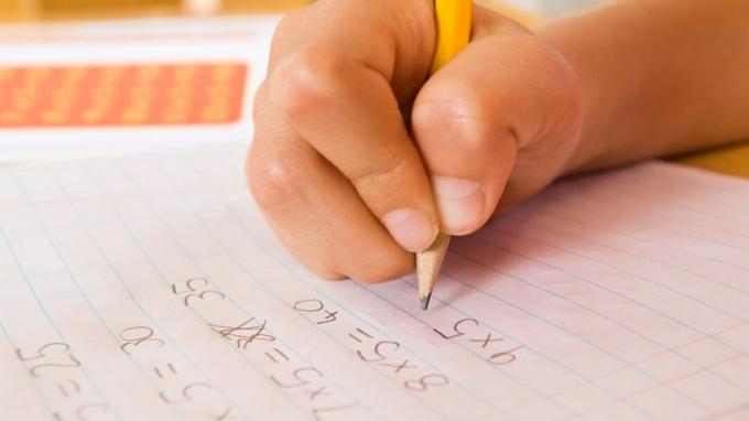 يد الطفل تستكمل مهمة الواجب المنزلي بمساعدة مساكن الرياضيات